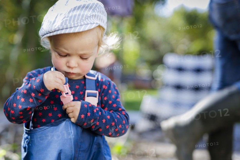 Toddler tries to close the fastener of a pair of play trousers, Bonn, Germany, Europe