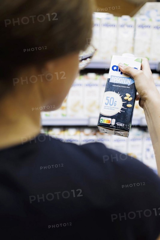 Younger woman buys a protein drink in a supermarket. Radevormwald, Germany, Europe