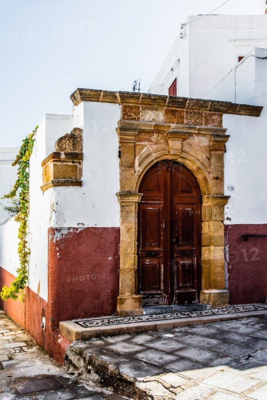 Old wooden doors with pebble mosaics on the floor, winding streets with white houses, Lindos, Rhodes, Greece, Europe