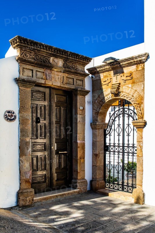 Old wooden doors with pebble mosaics on the floor, winding streets with white houses, Lindos, Rhodes, Greece, Europe
