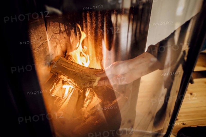Symbolic photo: A woman throws a log into a fireplace. Berlin, 03.03.2023, Berlin, Germany, Europe