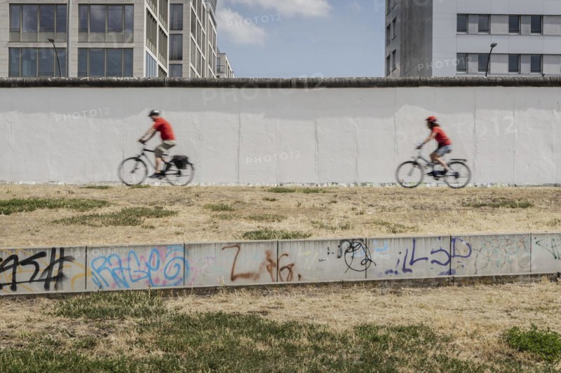 Two cyclists at the Berlin Wall stand out at the East Side Gallery in Berlin, 26.06.2022., Berlin, Germany, Europe