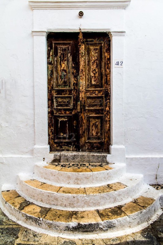Old wooden doors with pebble mosaics on the floor, winding streets with white houses, Lindos, Rhodes, Greece, Europe