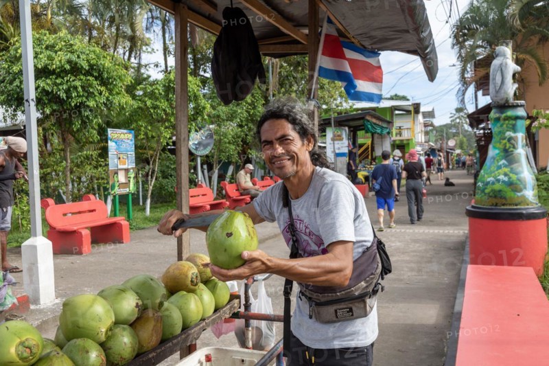 Tortuguero, Costa Rica, A street vendor cuts open a green coconut for a tourist in this small village on the Caribbean coast. The refreshing coconut water inside this then sipped through a straw, Central America