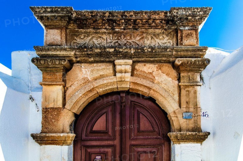 Old wooden doors with pebble mosaics on the floor, winding streets with white houses, Lindos, Rhodes, Greece, Europe