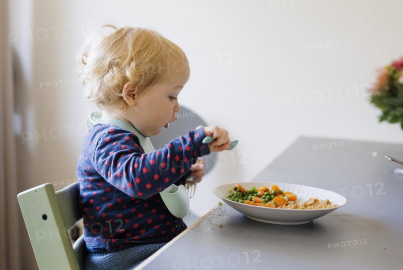 Bonn. Toddler eats a meal of peas, carrots and cereals. Bonn, Germany, Europe