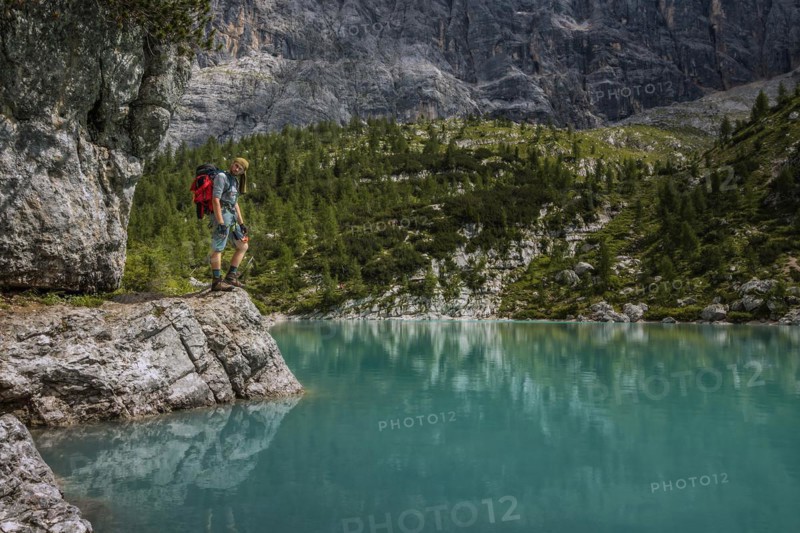 Tourist posing for a photo against the background of the beautiful Lago di Sorapis lake in the Italian Dolomites
