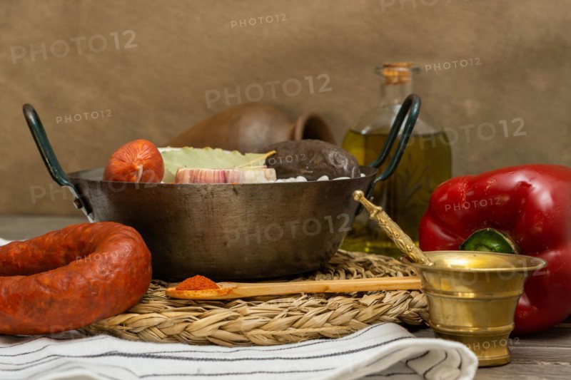 Raw white beans in metal casserole with all the ingredients for cooking them
