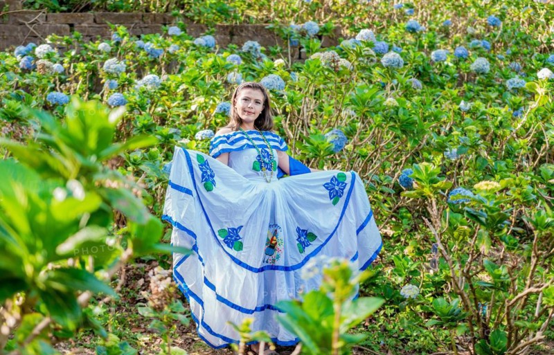 Portrait of young Nicaraguan woman in traditional folk costume in a field of flowers