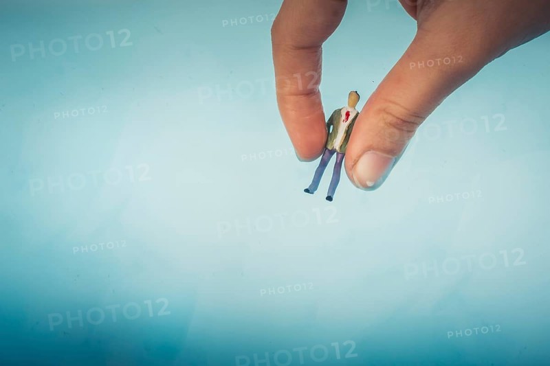 Hand holding a model airplane and a man figurine in blue water