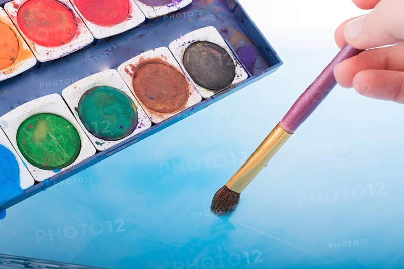 Watercolor paint dissolving in water as painting brush touches water