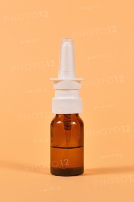 Brown glass nasal spray bottle on yellow background