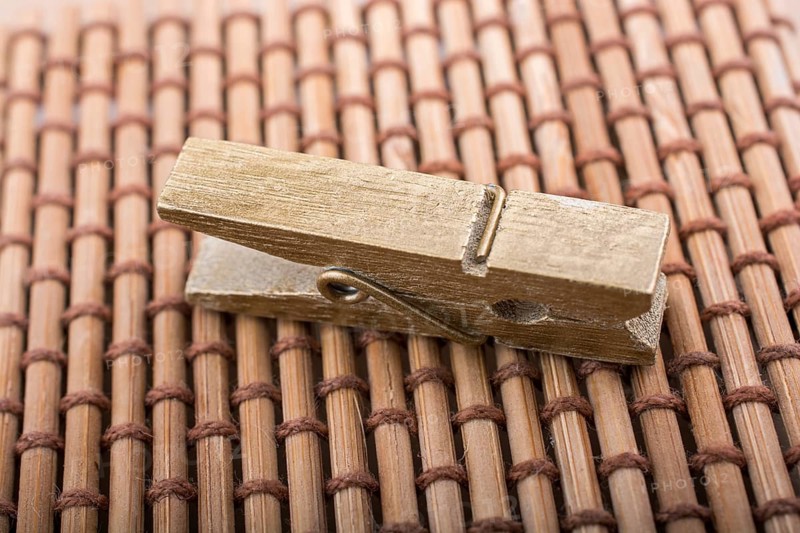 Small wooden clothespin placed on straw background