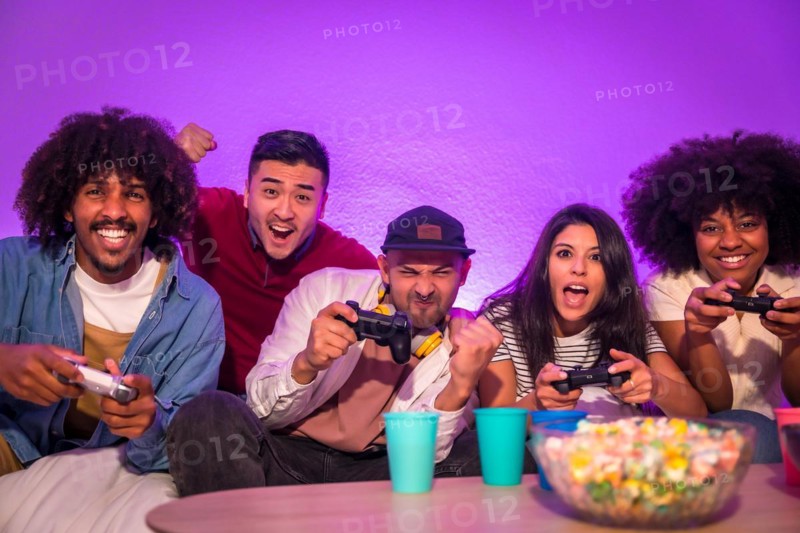 Adult party. Attractive young men sitting on the sofa playing video games with popcorn. With the joystick or controller in hand and look at the monitor