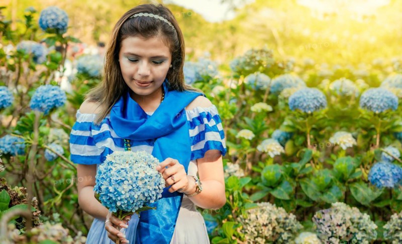 Nicaraguan girl in traditional folk costume holding flowers in a nursery. Beautiful Nicaraguan woman in national folk costume holding flowers in a nursery. Nicaraguan folk costume
