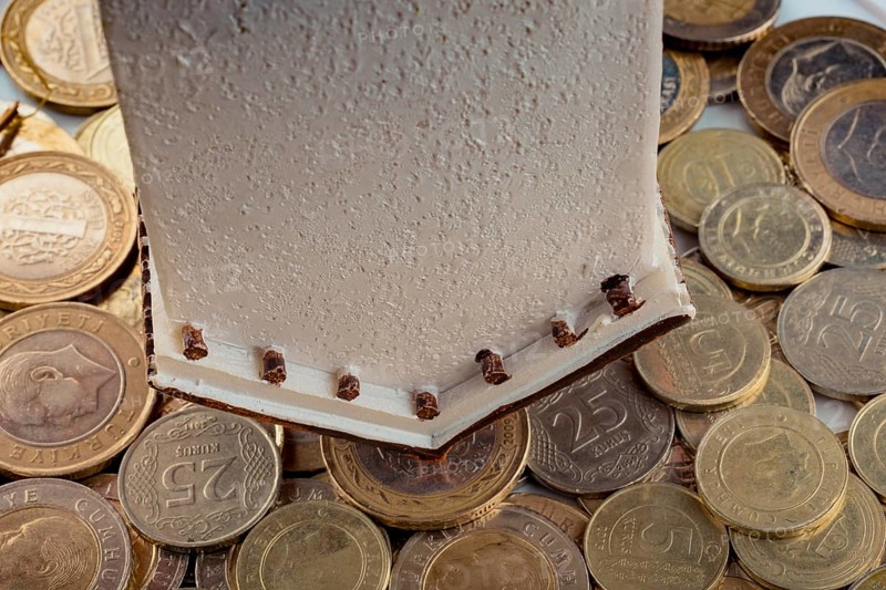 Turkish Lira coins by the side of a model house on white background