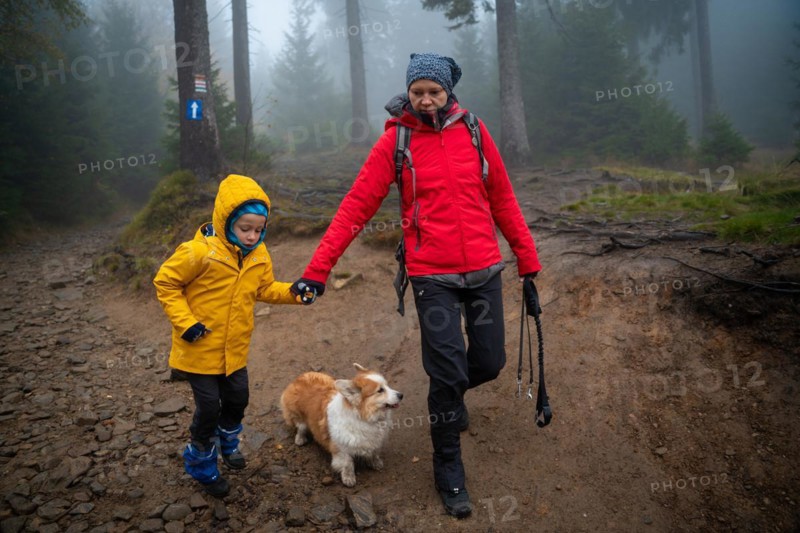 Mum and her little son go on a mountain trail in wet autumn weather. They are accompanied by a dog. Polish mountains
