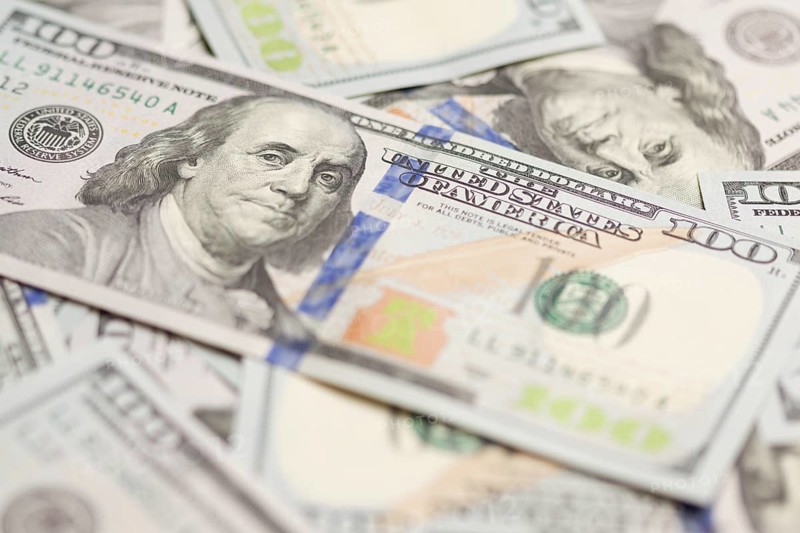 One hundred dollar bills laying on flat surface