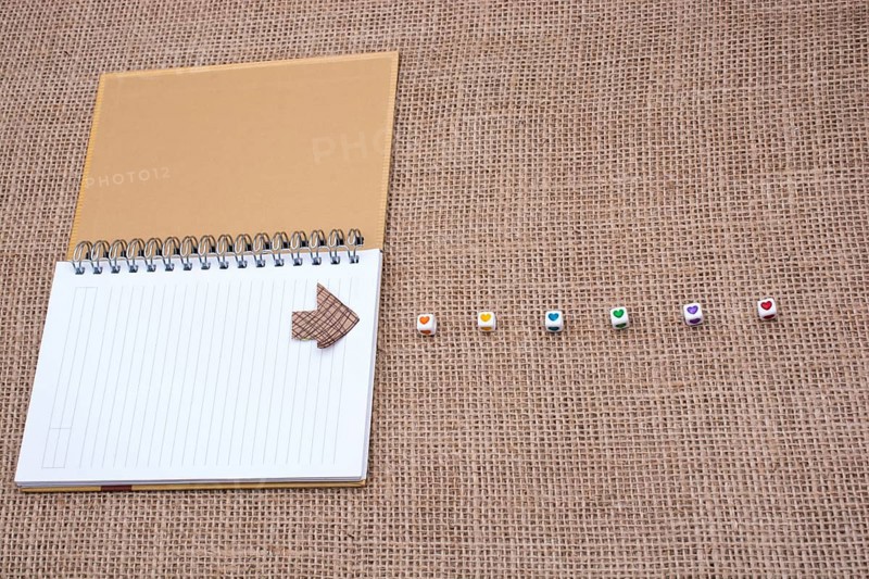 Love cubes and paper arrow on a notebook on canvas
