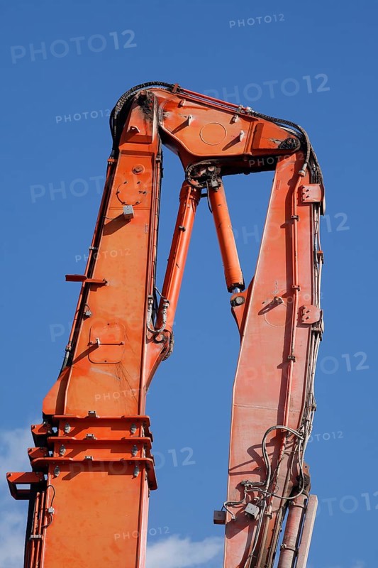 Orange hydraulic excavator arm of an excavator on a construction site