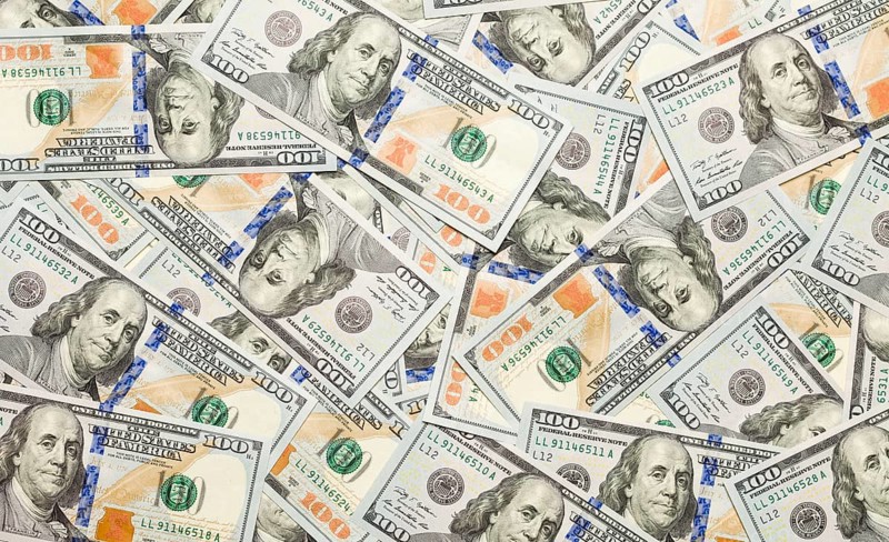 One hundred dollar bills laying on flat surface