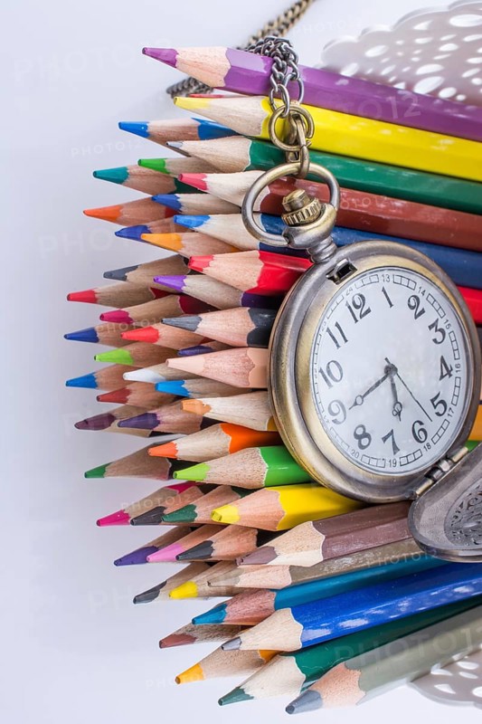 Retro style classic pocket watch and color pencils on white background