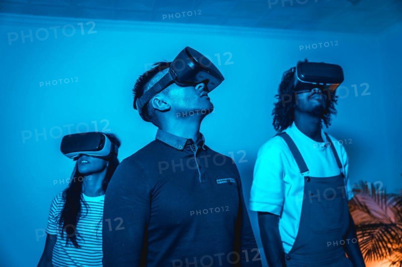 Group of young people with vr glasses in a virtual reality game in a blue light