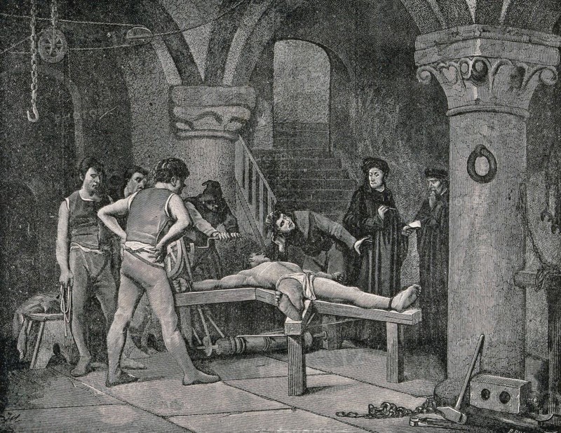 A man dressed in a loincloth is tortured on the rack while a priest bends over him to extract a confession