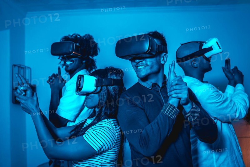 Group of young people in vr glasses in a virtual reality game in a blue light with guns
