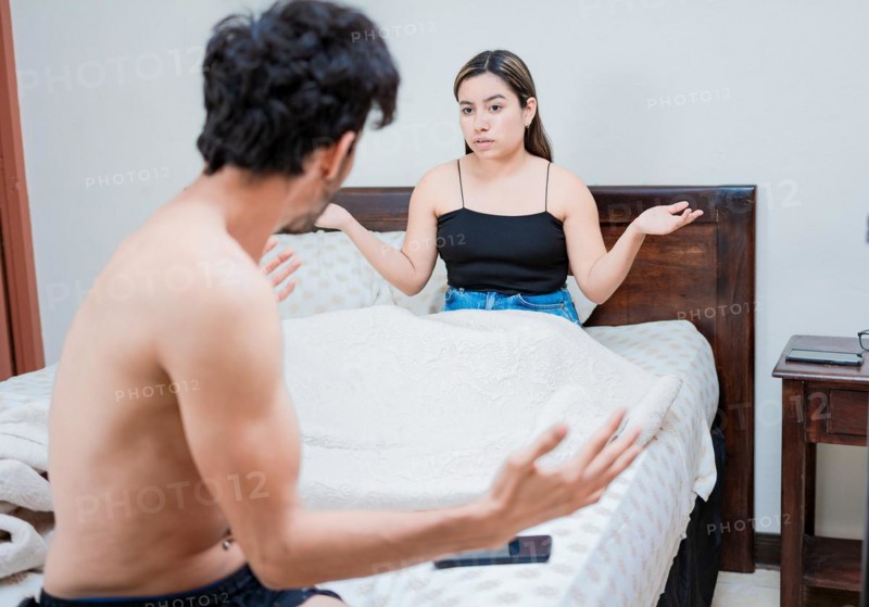 Upset wife with husband in bedroom bed