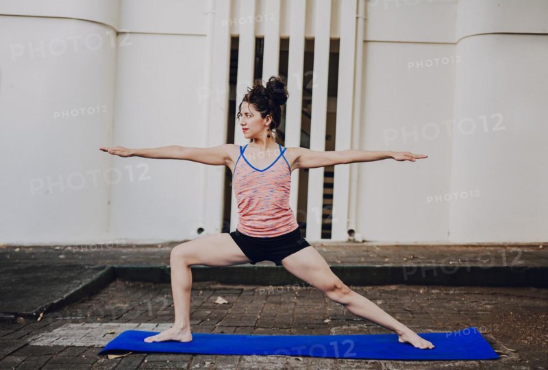 Girl practicing yoga Warrior II pose outdoors. Latin woman doing yoga warrior pose outdoors. Young woman doing yoga virabhadrasana II outdoors