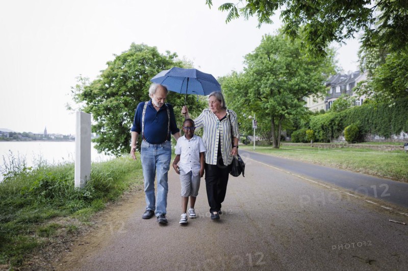 Temporary grandparents. Elderly couple volunteer to look after a boy from Africa for a few hours a week.