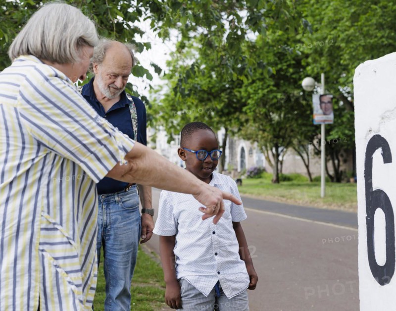 Temporary grandparents. Elderly couple volunteer to look after a boy from Africa for a few hours a week.