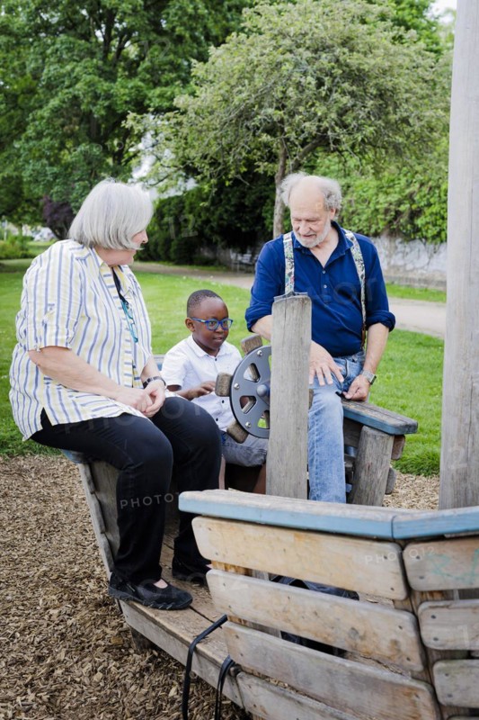Temporary grandparents. Elderly couple volunteer to look after a boy from Africa for a few hours a week.