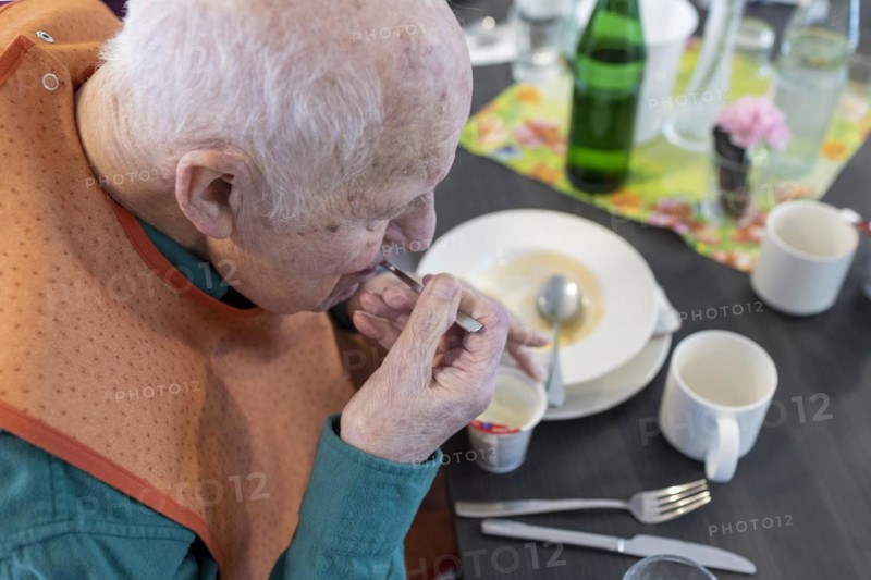 Old man in nursing home spooning a dessert