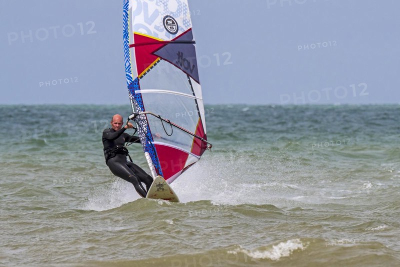 Recreational windsurfer in black wetsuit practising classic windsurfing along the North Sea coast