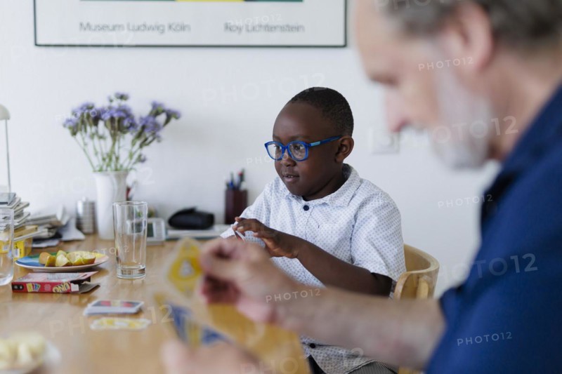Temporary grandparents. Elderly couple volunteer to look after a boy from Africa for a few hours a week.
