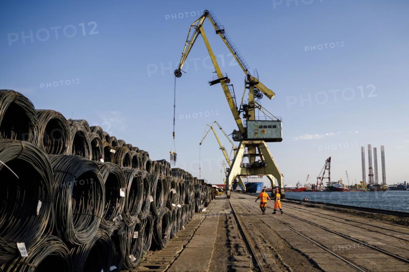 Dock workers walk past rolls of steel wire on the quay in Constanta harbour. Constanta