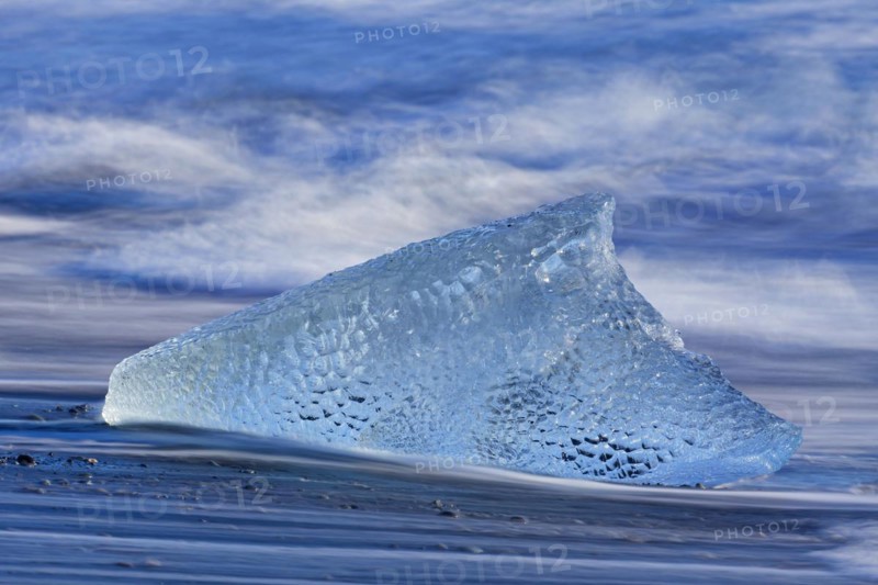 Melting block of ice washed on beach along the Atlantic Ocean coastline at Breidamerkursandur black sands in winter