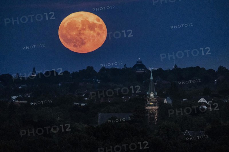 The so-called strawberry moon looms as it rises in Berlin