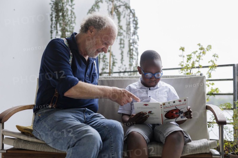 Temporary grandparents. Grandfather volunteers to look after a boy from Africa for a few hours a week.