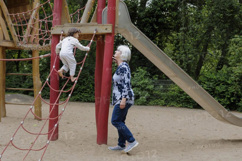 Volunteer. Temporary grandmother with a child in the playground.
