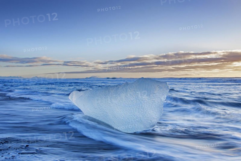 Melting block of ice washed on beach along the Atlantic Ocean coastline at Breidamerkursandur black sands in winter