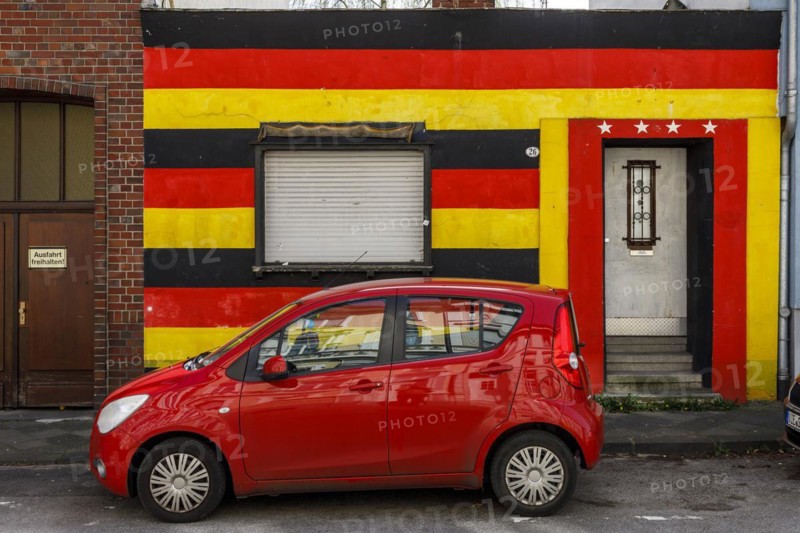 Front of a residential building in the German national colours black-red-gold and 4 stars above the entrance door