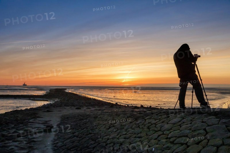 Tourist with camera during sunset on the Trischendamm