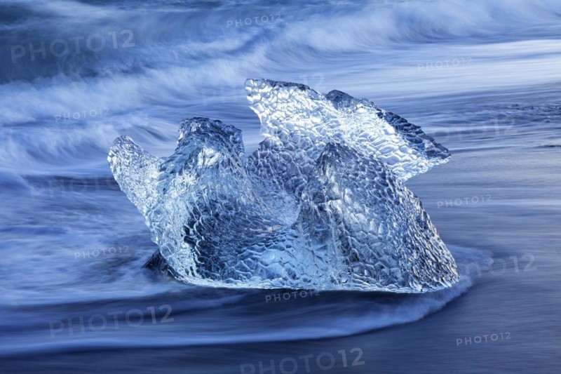Melting block of ice washed on beach along the Atlantic Ocean coastline at Breidamerkursandur black sands in winter