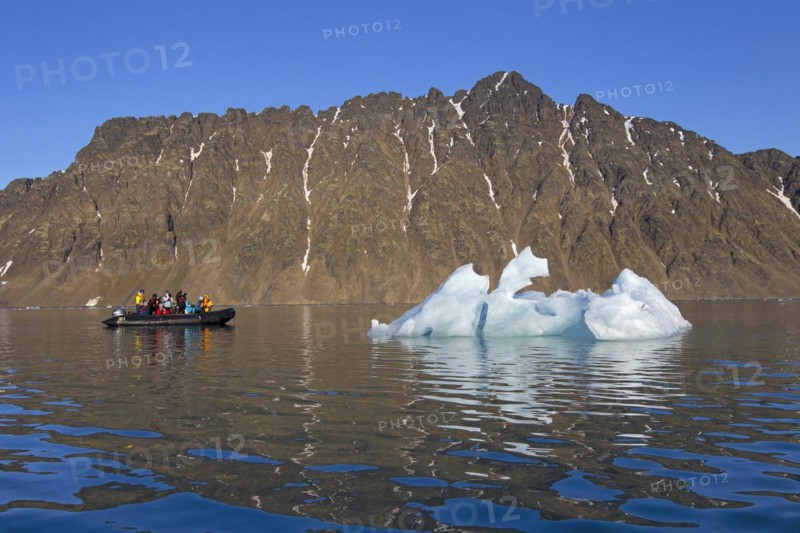 Eco-tourists in zodiac boat photographing melting iceberg in the Lilliehoeoekfjorden