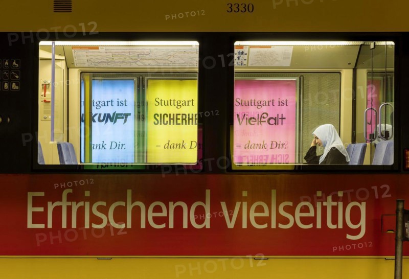 The city advertises diversity on posters. A Muslim woman wearing a headscarf sits on a city tram advertising a diverse product