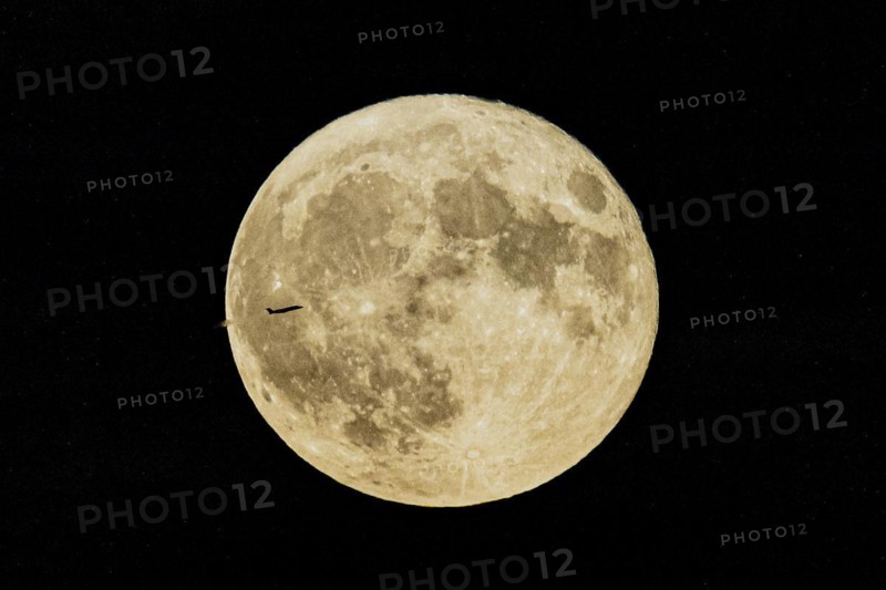 A plane looms in front of the so-called strawberry moon looms as it rises in Berlin