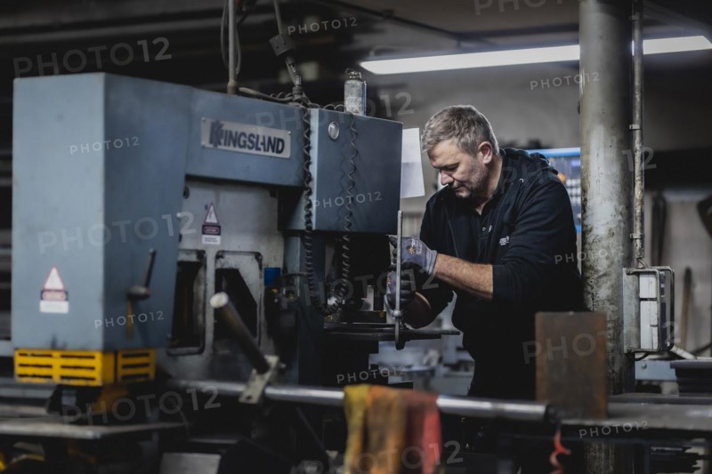 A metal worker clamps a piece of metal into a machine